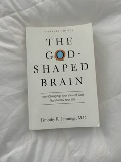 the god - shaped brain book is laying on a white bed sheet and it's title reads, the god - shaped brain