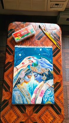 a painting is being displayed on a table with some pens and pencils next to it