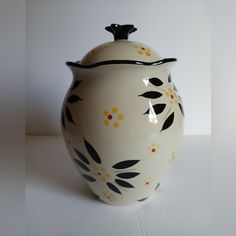 a white vase with black and yellow flowers painted on it