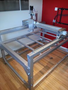 a metal bed frame sitting on top of a hard wood floor next to a red wall