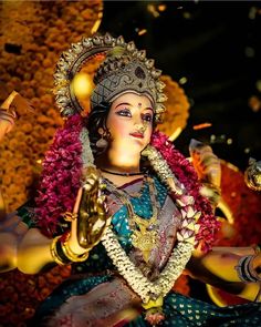 a statue of the hindu god ganesha in front of flowers and petals on display