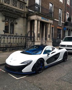 a white and blue sports car parked on the side of the road in front of a building