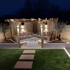 an outdoor living area lit up at night, with grass and stepping steps leading to the seating area