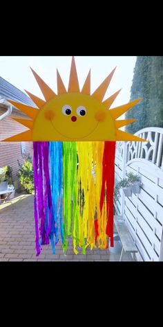 a paper sun that has been made into a rainbow streamer hanging from the side of a house