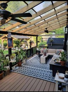 an outdoor living area with lots of plants and furniture on the deck, covered by a pergolated roof