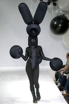 a woman is walking down the runway with balloons in the air and an bunny costume on