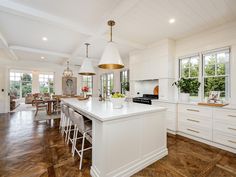 a large kitchen with white cabinets and wood flooring, along with an island in the middle