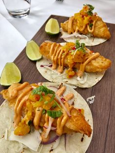 three fish tacos on tortillas topped with sauce and garnishes