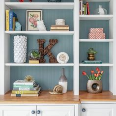 two white bookcases filled with books and vases