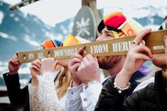 a group of people standing next to each other holding up signs that say downhill from here