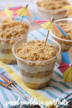 three desserts in plastic cups on a table with colorful umbrellas sticking out of them