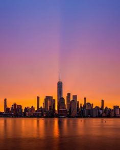 the sun is setting in front of a large city with tall buildings and skyscrapers