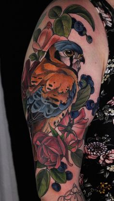 a woman's arm with an owl and flowers tattoo on her left arm, next to a black background