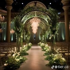 an indoor wedding venue with chandeliers and flowers on the aisle, surrounded by greenery