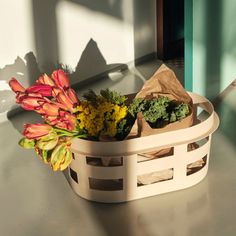 a basket filled with flowers sitting on top of a table next to a window sill