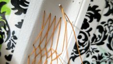 an orange string is attached to the side of a white wall with black and green designs on it