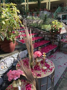 flowers and candles sit on tables in the middle of an outdoor area with stone steps