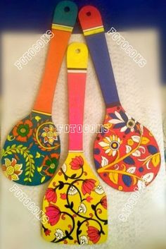 three colorful paddles are hanging on the wall with flowers and leaves painted on them