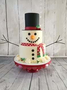 a snowman cake sitting on top of a red and white plate covered in frosting