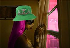 a woman with pink hair wearing a green hat and sunglasses, standing next to a window