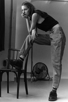 black and white photograph of a woman sitting on a chair with her hand in her mouth