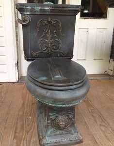 an old toilet is sitting outside on the wooden floor in front of a white door