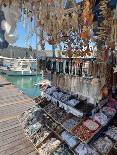 an outdoor market with lots of necklaces and bracelets on display in front of the water