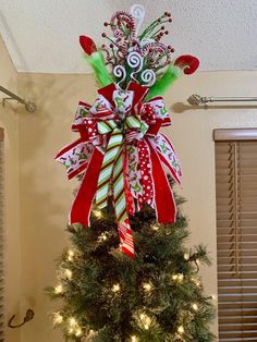 a decorated christmas tree with candy canes and bows on it's top, hanging from the ceiling