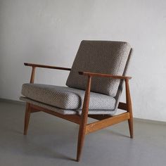 a chair sitting on top of a cement floor next to a white wall with a wooden frame