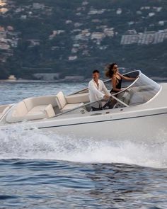 a man and woman riding on the back of a white boat