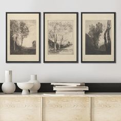 three black and white paintings hang above a dresser