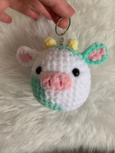 a crocheted cow keychain hanging on a white furnishing surface