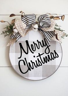 a merry christmas sign hanging on the side of a wall with ribbon and bow around it