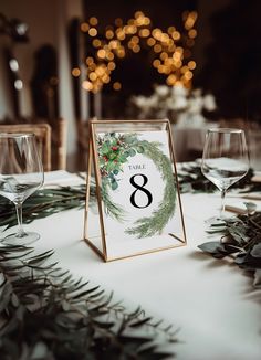 the table is set with wine glasses and greenery for an elegant winter wedding reception