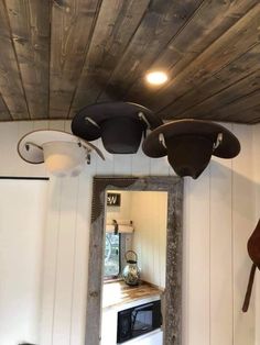 a kitchen area with a sink, microwave and mirror on the wall next to a wood plank ceiling