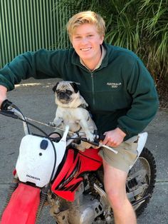 a young man is sitting on a motorcycle with his pug