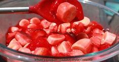 a bowl filled with sliced up strawberries and sauce being poured over them to make strawberry jello