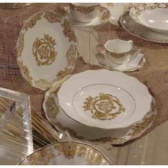 a table topped with lots of white and gold china dishes covered in golden trimmings