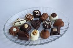 a glass plate filled with assorted chocolates on top of a table