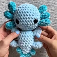 someone is holding a small blue crocheted stuffed animal