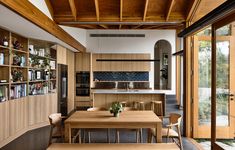 an open kitchen and dining room area with wood paneled walls, wooden flooring and built - in bookshelves