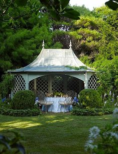 an outdoor gazebo with tables and chairs in the middle of it, surrounded by greenery