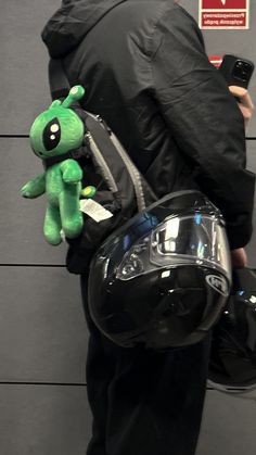 a person wearing a helmet and holding a cell phone with a stuffed animal attached to it