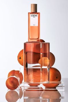 a bottle of perfume sitting on top of oranges in front of a white background