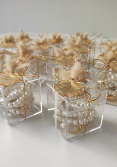 small clear boxes filled with pearls and gold ribboned bowknots on white surface