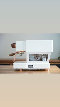 a white coffee machine sitting on top of a wooden table