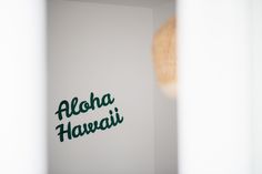 the name aloha hawaii is written in green on a white wall