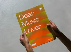 two hands holding up a book that says dear music lover, one is orange and the other is green