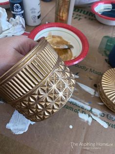 a person is holding a gold cup in front of some plates and cups on the table