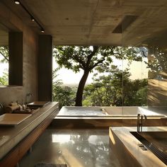 a bathroom with two sinks and a bathtub next to a tree in the background